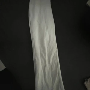 Vita mjukisbyxor med resårmidja - Säljer ett par vita mjukisbyxor med bred resår i midjan och metallöljetter för eventuell snörning. Byxorna har en rak passform och är perfekta för en avslappnad stil.