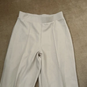 Beige  byxor fårn Gina tricot  - Snygga beige byxor med hög midja och vida ben. Byxorna har en slät front och bred linning för en stilren look.  Köpta från Gina tricot .