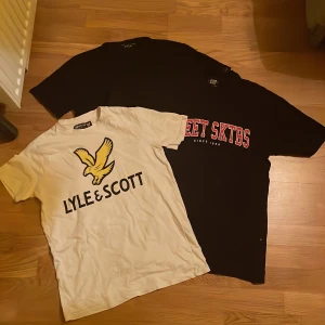 T-shirts - Vit t-shirt med stort gult fågeltryck och svart Lyle & Scott-logga på bröstet. Klassisk rund hals och korta ärmar. Perfekt för en avslappnad stil. Renar garderoben och hittade dessa plagg, försöker få in lite pengar till sommaren