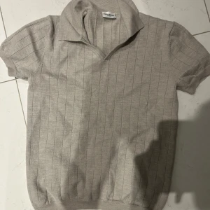 Beige stickad pikétröja från John Henric - Säljer en stilren beige stickad pikétröja från John Henric i storlek M. Tröjan har korta ärmar, krage och diskreta vertikala ränder. Perfekt för en avslappnad men snygg look. Är tvättad på fel sätt skulle säga att den passar s