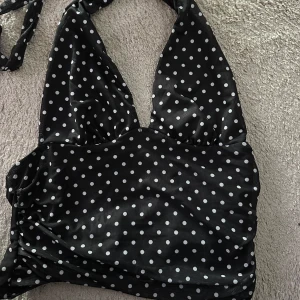 Prickig halterneck topp  - Säljer en svart halterneck topp från SHEIN med vita prickar. Toppen knyts i nacken och är därmed justerbar. Storlek L och är aldrig använd🖤🤍