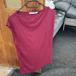 Vinröd ärmlös topp - En enkel vinröd topp i ärmlös modell. Toppen har rund halsringning och är tillverkad i ett mjukt material som känns skönt mot huden. Perfekt att matcha med jeans eller kjol för en stilren look.