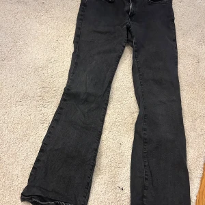 Svarta jeans från Gina tricot - Svarta jeans från Gina tricot med klassisk femficksdesign och raka/utsvängda ben. Jeansen har normal passform och är tillverkade i ett stretchigt denimtyg som gör dem bekväma att bära hela dagen.
