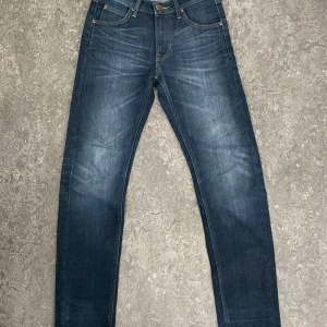 Mörkblå Lee jeans - Snygga mörkblå jeans från Lee med klassisk femficksdesign och raka ben. Jeansen har Lee-lapp i läder baktill och kontrastsömmar. Perfekta för dig som gillar en tidlös look och vill ha ett par jeans som funkar till allt. Kosta 1400kr nya knappt använda så 500kr är bra pris 