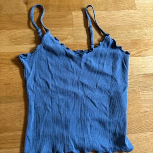 Blå ribbad linnetopp från Hollister - Supersöt blå ribbad linnetopp från Hollister med smala axelband och vågig kant upptill och nedtill