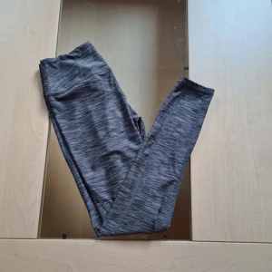 Gråmelerade leggings med hög midja - Snygga gråmelerade leggings med hög midja och smal passform. De är tillverkade i ett stretchigt syntetmaterial som sitter tajt och bekvämt. Perfekta för träning eller chill. Mönstret är diskret melerat och färgen går i olika grå toner.