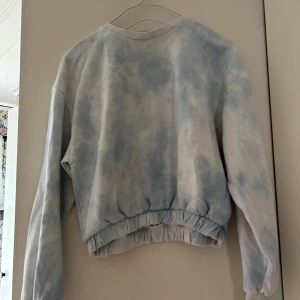 Ljusblå batiktröja från 157 - Säljer en chill ljusblå och vit batiktröja från 157 i storlek XS/S. Tröjan har långärmade ärmar, rund hals och elastisk midja som ger en snygg passform. Perfekt för dig som gillar softa och avslappnade vibes.