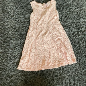 Ljusrosa spetsklänning från Ellos - Supersöt ljusrosa klänning från Ellos med blommigt spetsmönster och ärmlös design. Klänningen har rund halsringning och är fodrad med ett mjukt tyg som gör den extra bekväm. Perfekt för vår och sommar när du vill känna dig extra fin.