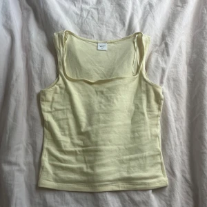 Ljusgul linnetopp från Gina Tricot - Supersöt ljusgul linnetopp från Gina Tricot, Elevated Basics. Toppen har smala axelband och en enkel, rak passform som är perfekt till sommaren. Mjuk och skön bomullskänsla, lätt att matcha med jeans eller kjol.