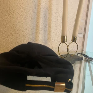 Navy blå keps från Hugo Boss - Snygg svart keps från Hugo Boss med gul broderad BOSS-logga framtill. Justerbar rem med gul detalj och metallspänne baktill. Klassisk formad skärm och ventilerande insida. Perfekt för dig som vill ha en stilren och cool accessoar.