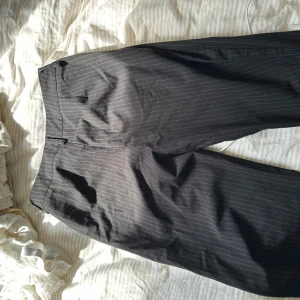 Randiga kostymbyxor från Madlady - Snygga svarta kostymbyxor från Madlady med tunna vita ränder. Byxorna är mid/low waist, raka ben. Perfekta för en clean och stilren look.