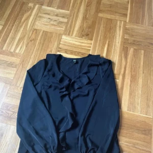 Svart blus med volanger - Jättefin blush med volanger fram. Aldrig använd