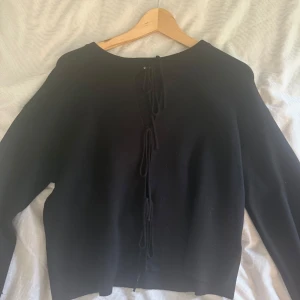 Svart stickad tröja med snörning - Svart stickad tröja från Gina tricot med snygg snörningsdetalj i ryggen. Tröjan har lång ärm och en rak, lite loose passform. Perfekt för dig som gillar stilrena plagg med en twist. Enkel att matcha med både jeans och kjol.