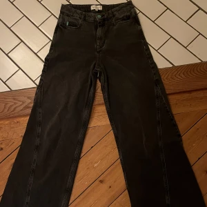 Svarta wide jeans från Fabienne Chapot - Snygga svarta jeans från Fabienne Chapot med raka, vida ben och coola sömdetaljer längs benen. Klassisk femficksmodell med hög midja och knapp med logga. Perfekta för dig som gillar en avslappnad men trendig look.