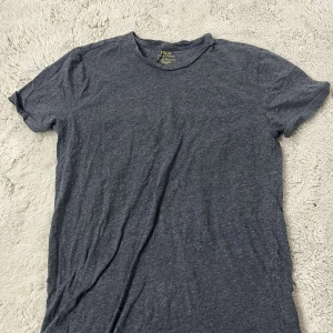 Mörkgrå t-shirt från Polo Ralph Lauren - Snygg mörkgrå t-shirt från Polo Ralph Lauren i klassisk modell med rund hals och korta ärmar. Tillverkad i mjuk bomull som känns skön mot huden. Perfekt för dig som gillar stilrena och enkla plagg med premiumkänsla.