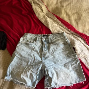 Ljusblå jeansshorts från 157 XS - Säljer ett par ljusblå jeansshorts från 157 i storlek XS. De har klassisk femficksdesign, råa kanter nertill och dragkedja med knapp. Perfekta för chill dagar och har en loose passform som ger skön vibe.