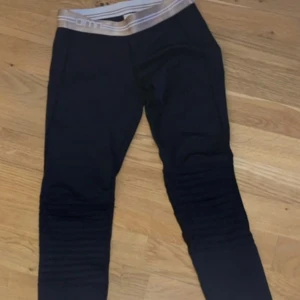 Svarta leggings från Aim'n XS - Svarta leggings från Aim'n i storlek XS med bred, beige resår i midjan. Byxorna har ribbade detaljer över knäna och är tillverkade i stretchigt material med 73% polyester och 27% spandex. Perfekta för träning eller chill.