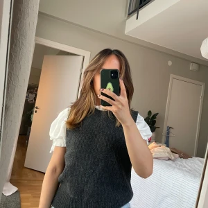 Mörkgrå stickad väst från ONLY - Mörkgrå stickad väst från ONLY i ribbat material. Klassisk rund halsringning och rak passform, perfekt att slänga över en skjorta eller t-shirt. Västen är gjord av ullblandning med polyester och viskos för en mjuk känsla.