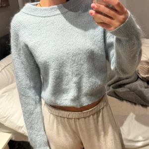 Ljusblå stickad tröja från Lindex - Supermysig ljusblå stickad tröja från Lindex i storlek S. Tröjan har en croppad passform, rund halsringning och långa ärmar. Perfekt för lager-på-lager och chill dagar. Mjuk och fluffig känsla som gör den extra skön att bära.