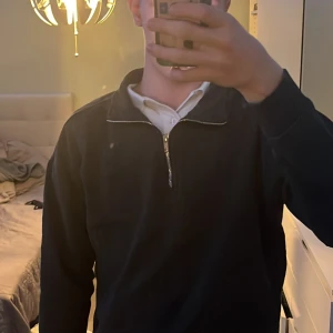 Svart half zip tröja från 157 - Svart långärmad tröja från 157 med halv dragkedja och hög krage. Insidan är mjuk och fleecefodrad vilket gör den extra skön. Perfekt för kyliga dagar och enkel att matcha med jeans eller joggers. Säljer den för den är förliten och vill sälja den snabbt.