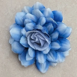 Blå blomformad brosch/hårklämma - Snygg blå blomformad brosch som även kan användas som hårklämma. Blomman har flera lager av blå och vita kronblad med diskret glitter på kanterna. Fästet på baksidan gör att du kan använda den både som brosch och håraccessoar. Perfekt för att ge din outfit en färgklick.