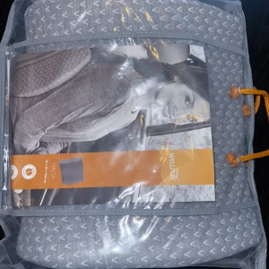 Ländryggskudde - Mått: 34 × 36 × 12 cm. Ergonomisk kudde i tryckavlastande memoryskum med fuktabsorberande bambukol. Avtagbart överdrag i 100% polyester, tvättbart i 60°C. Helt ny och oanvänd.