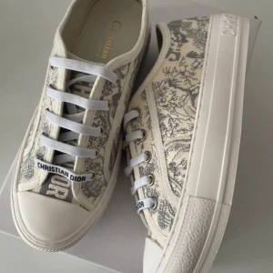 Christian Dior sneakers med mönster - Snygga sneakers från Christian Dior i beige och grått med unikt blommigt mönster. Helt nya och låda följs med