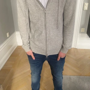 Ljusgrå hoodie i kashmir från John Henric - Säljer en supermjuk och lyxig ljusgrå hoodie från John Henric i 100% kashmir. Tröjan har dragkedja framtill, huva med snören och ribbade muddar. Storlek M. Nypris 2500, säljer för 500. Kan ändra pris vid snabbt köp! Det finns 2 defekter med plagget därav de låga priset