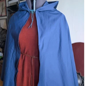Blå mantel med luva - Handsydd mantel. Bomullsatin. Tunn. Kan ta mer bilder. 70cm lång. Luva 40cm. Mjuk. Vacker blå. Möts i Gbg. Ingen brosch. Passar st 36 till 40. 400kr eller byte.