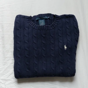 Ralph Lauren stickad tröja - Fast pris✅️. Säljer en blå ralph lauren cable knit tröja som är blå med vitt märke, knappt använd.