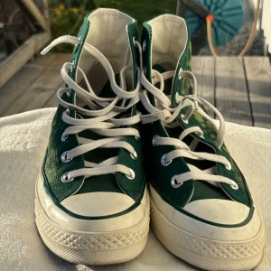 Gröna converse  - Jättefina, gröna converse med blomstermönster på! Perfekta på våren och inför sommaren! Använda ett fåtal gånger men är i väldigt bra skick. Kan sänka pris vid snabb affär!