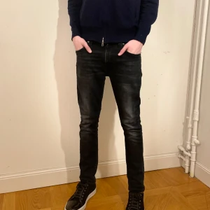 Svarta Nudie Jeans - Jag säljer nu dessa sjukt snygga Nudie jeansen som är i mycket bra skick! Modellen heter Grim Tim och är i storlek 29/32. Referens-killen på bilden är 180 cm lång och väger 65 kg! Hör gärna av er vid frågor eller funderingar 😃