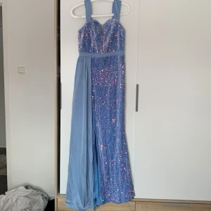 Blå glittrig långklänning med släp - Säljer en blå långklänning med breda axelband och hjärtformad urringning. Klänningen är täckt av glittriga paljetter och har ett elegant släp i chiffongliknande material. Perfekt för bal eller festkväll! 