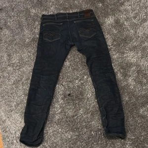 Mörkblå Replay jeansbyxor - Säljer ett par mörkblå jeans från Replay med klassisk femficksdesign och snygga kontrastsömmar. Byxorna har raka ben och detaljerade bakfickor med dekorativ söm. Perfekta för dig som gillar stilrena jeans med bra passform.