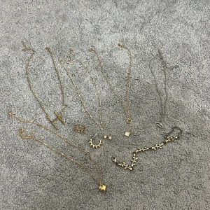 Packet med guldiga smycken  - Säljer ett set med flera guldiga smycken: halsband med H-berlock, halsband med fyrkantiga hängen, guld kedja, silver halsband med fjärli och halsband med hjärtberlock💕 Ring med romerska siffror, örhängen och ett armband (vissa saker är rost fritt men inget är riktigt guld)🥰