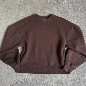 Brun sweatshirt från Gina Tricot - Mysig brun sweatshirt från Gina Tricot, basically basics-kollektionen. Tröjan har rund halsringning, långa ärmar och breda muddar vid ärmslut och nederkant. Perfekt för en avslappnad stil.