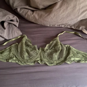 Olivgrön spets-bh från Hunkemöller - Säljer en olivgrön bh från Hunkemöller i vacker spets. Bh:n har tunna axelband och fina spetsdetaljer över hela kuporna. Perfekt för dig som gillar en feminin och stilren look.