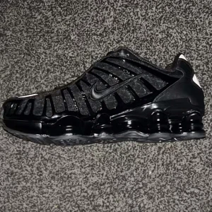 Nike Shox svarta  - Säljer ett par helsvarta Nike Shox sneakers med ikonisk fjädrande sula och diskreta röda detaljer på plösen. Skorna har snörning, mesh- och syntetpaneler samt en sportig, futuristisk look. Perfekta för dig som gillar streetwear och vill sticka ut.