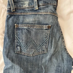 Blå bootcut jeans från Wrangler - Säljer dessa sjukt coola bootcut jeans från wrangler. Jeansen har snygga slitningar och najs sömmar på bakfickorna. (OBS köpare står för frakten.)💗💗