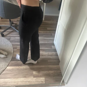 Svarta lågmidjadekostymbyxor från Atmosphere - Säljer ett par svarta kostymbyxor från Atmosphere med låg midja och raka ben. Byxorna har två knappar i midjan och fickor på sidorna. Perfekta för en clean och stilren look.