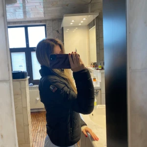 Svart pufferjacka från parajumper - Säljer en svart pufferjacka från parajumper med hög krage och diskret logga på ärmen. Jackan har dragkedja framtill och två fickor. Perfekt för kyligare dagar och enkel att matcha med olika outfits.