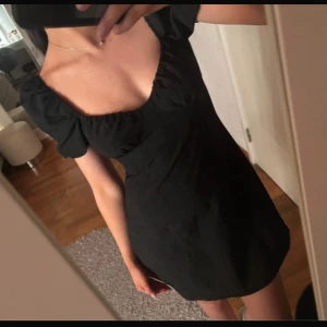 Svart kortklänning med puffärmar - Säljer en svart kortklänning med puffiga kortärmar och fyrkantig ringning. Klänningen har en figurnära passform och dragkedja i sidan. Perfekt för dig som gillar en stilren och trendig look. Nyskick! Skutsnygg ❤️‍🔥❤️‍🔥