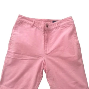 Rosa shorts från Polo Ralph Lauren - Ge din sommargarderob en färgklick med dessa stilrena rosa chinoshorts! Tillverkade i ett mjukt och bekvämt bomullstyg, erbjuder de både komfort och en snygg, avslappnad look. Shortsen har en klassisk design med gylf med knapp och dragkedja, bälteshällor samt diskreta sidofickor. Perfekta för både vardagliga utflykter och mer uppklädda tillfällen – kombinera med en vit skjorta för en fräsch sommarstil eller med en t-shirt för en mer avslappnad look.