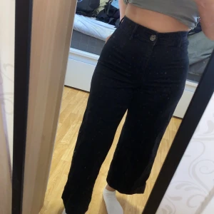 Svarta vida jeansbyxor - Säljer ett par svarta jeansbyxor med hög midja och vida ben. Byxorna har klassisk femficksdesign och stängs med knapp och dragkedja. Perfekta för en avslappnad men ändå trendig look.
