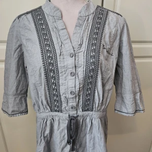 Bondelid grå blus nytt  - Superfin oanvänd grå blus med knappar, snörning i midjan och trekvartsärm.  Strl M
