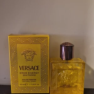 Versace Eros Energy pour homme Eau de Parfum 48/50 ml  - Versace Eros Energy pour homme är en lyxig herrparfym i en guldfärgad flaska med klassiskt Versace-mönster och Medusa-logga. Flaskan rymmer 50 ml och parfymen har en elegant och energisk doftprofil.