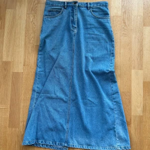Lång jeanskjol - Jättefin lång jeanskjol som tyvärr inte kommer till användning. Midjemått rakt över är 40cm, och längden från midja till botten av kjolen är 90cm. Den har en slit på baksidan som gör att man lättare kan gå i den! Går att ha den lågmidjad om man vanligtvis har storlek S🫶
