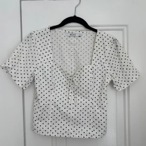 Vit prickig blus från NA-KD - Säljer en söt vit blus från NA-KD med svarta prickar!