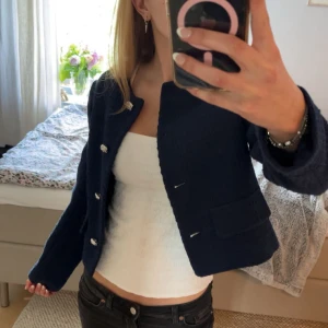 Mörkblå kavajjacka från Zara - Säljer en mörkblå kavajjacka från Zara i strukturerat tyg. Jackan har långa ärmar, dekorativa silvriga knappar framtill och två fickor. Klassisk och stilren modell som passar perfekt till många outfits. Köptes förra året, helt oanvänd. Köpt för 500. Skriv vid frågor🥰pris kan diskuteras!