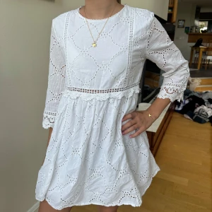 Vit broderad kort klänning  - Superfin vit kortklänning i bomull med broderade detaljer och spets vid ärmslut och midja. Klänningen har trekvartsärm och en luftig passform. Passar perfekt till studenten/ midsommar eller en sommardag! Klänningen är i M men skulle säga att den sitter bäst på en S/xs då den är ganska kort. 